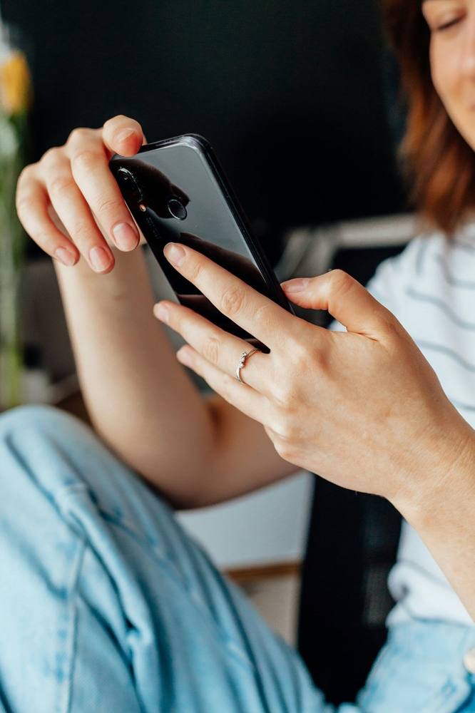 A woman relaxing at home, holding her phone for a video session